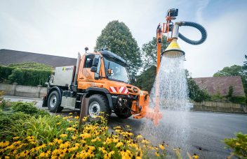 Mietfahrzeug erhältlich über Unimog Rent beim bewässern von Blumen