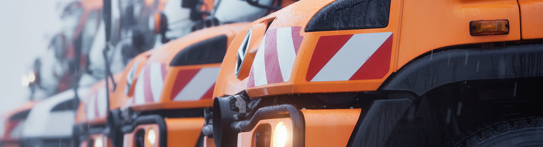 Mehrere Unimog im Regen geparkt.