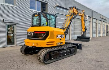 JCB 86C-2 mit Verstellausleger von hinten vor Werkstatt