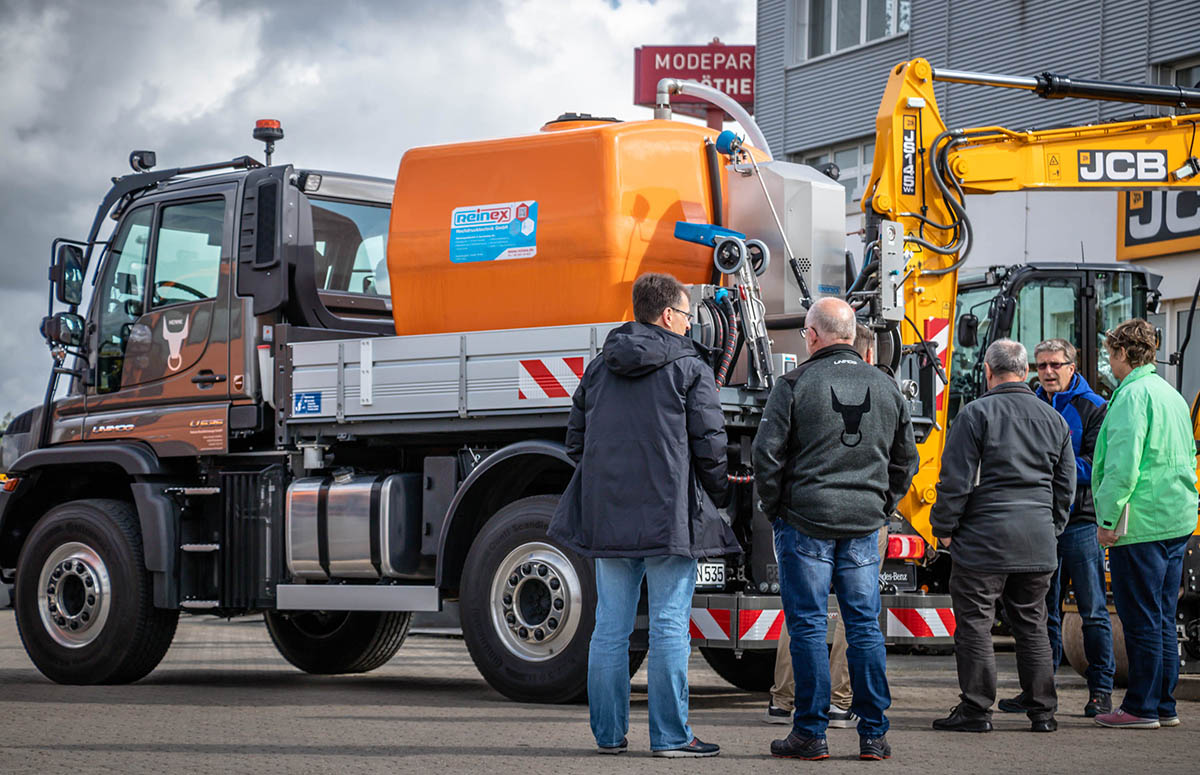 Kunde und Henne Verkäufer vor Unimog U 535 mit Reinex Wasserfass