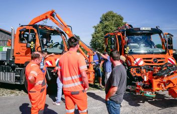 Besucher der Roadshow betrachten die Unimog mit Mähaufbau