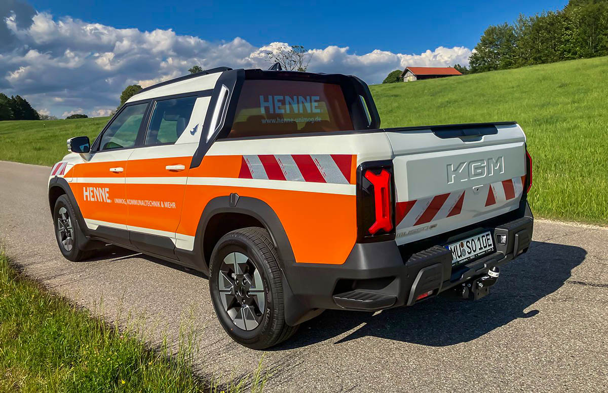 Heckansicht des KGM Musso EV mit offener Ladefläche und HENNE-Beklebung